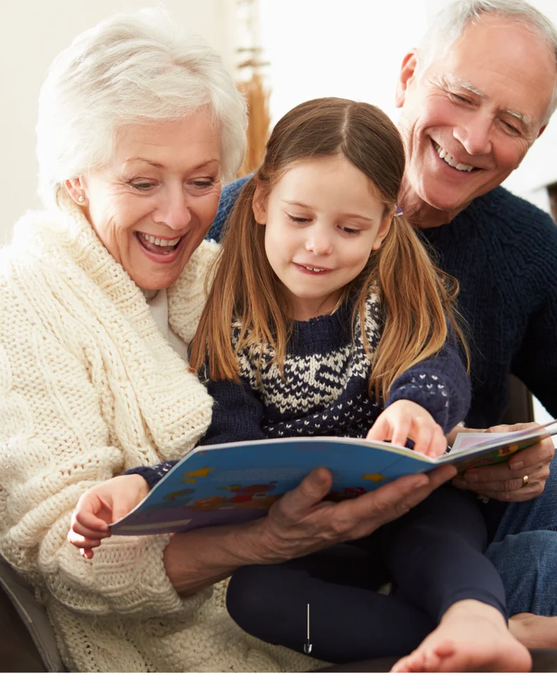 Grandparents sharing a storybook with their granddaughter